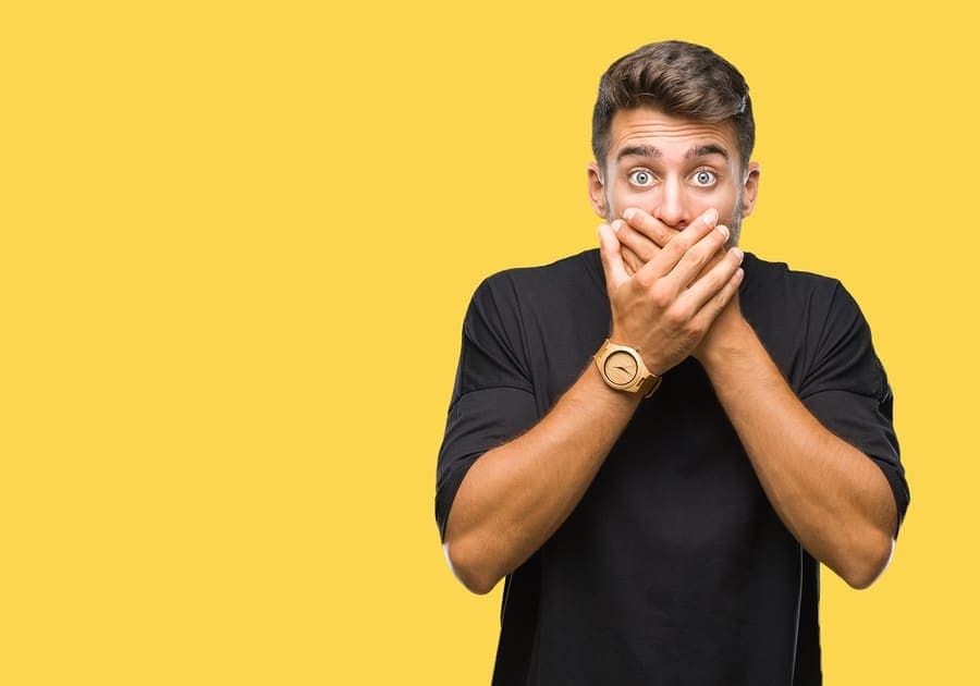 Man covering his mouth while checking his breath