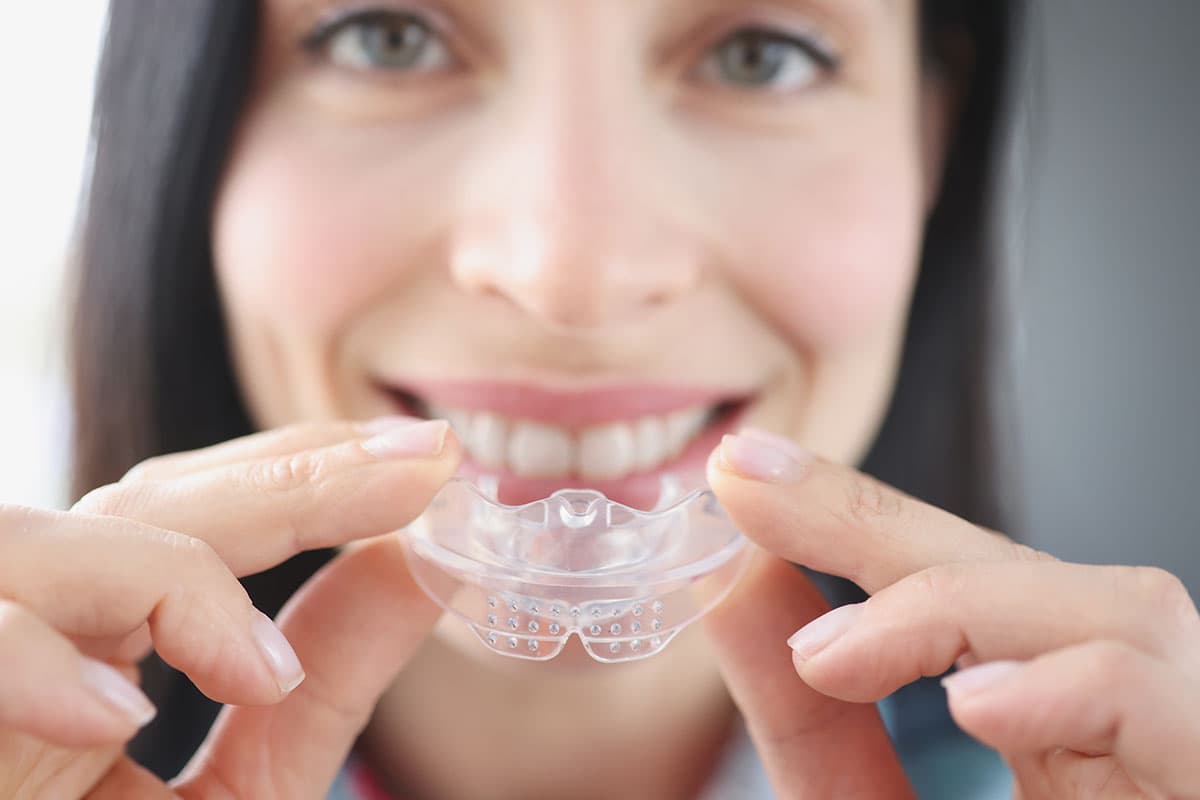 Woman holding a custom clear night guard at Advanced Dental Care Leesburg