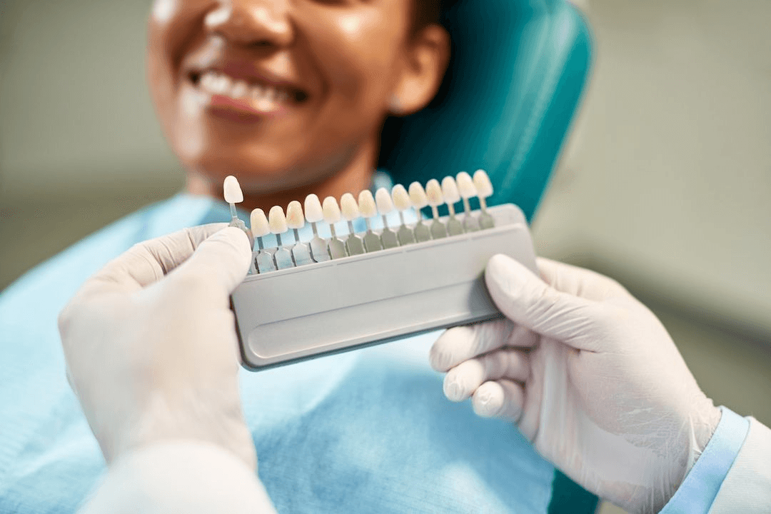 Dentist holding porcelain veneer shade guide for smiling patient at Advanced Dental Care Leesburg